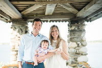 Luke Holden holding his young daughter and standing next to his wife.