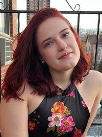 Jean posing for a picture outside a brick building while wearing a floral shirt