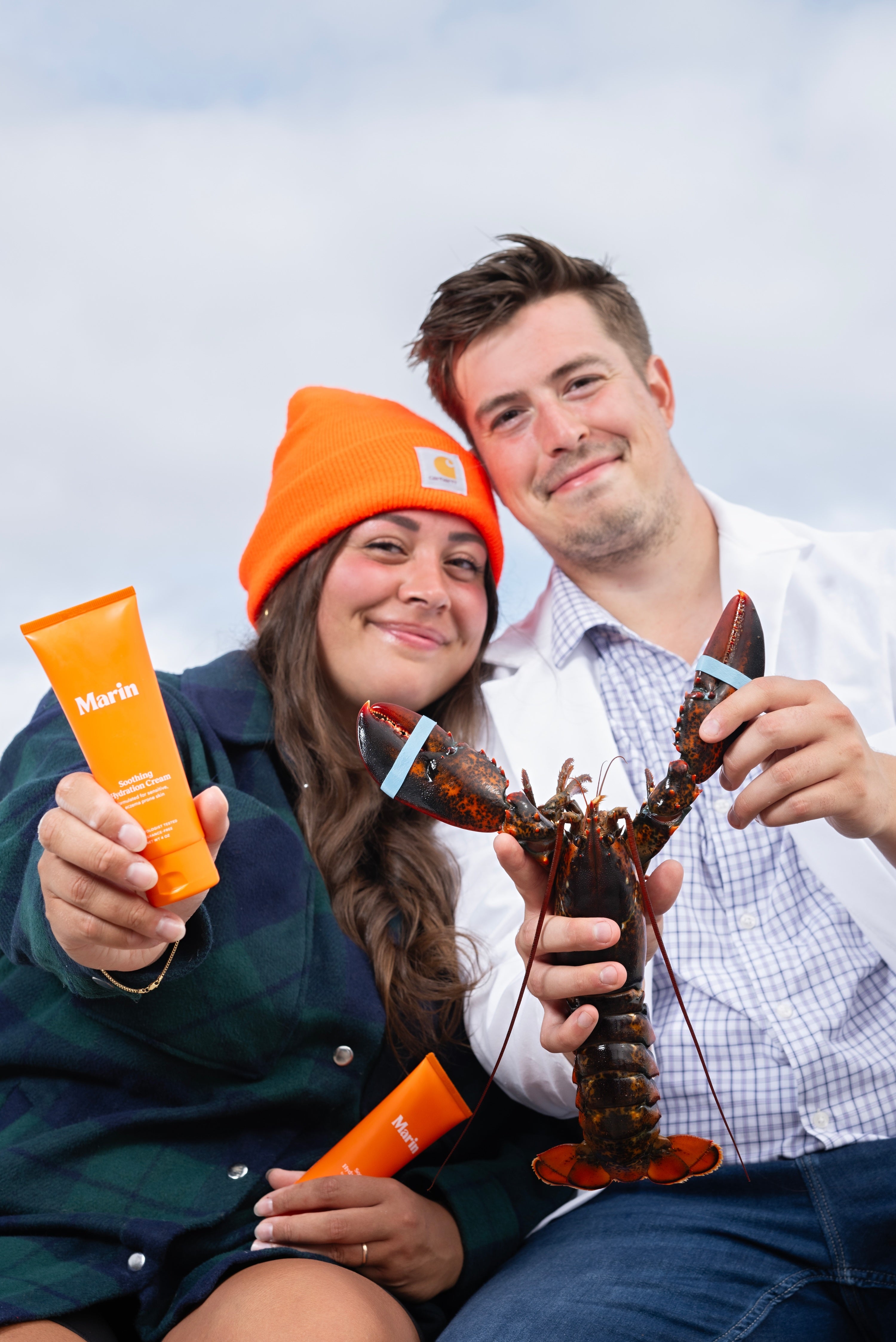 man and woman smiling holding lobster and glycoprotein skincare product