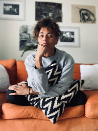 Addie Fisher sitting on a orange couch resting her head on her hand