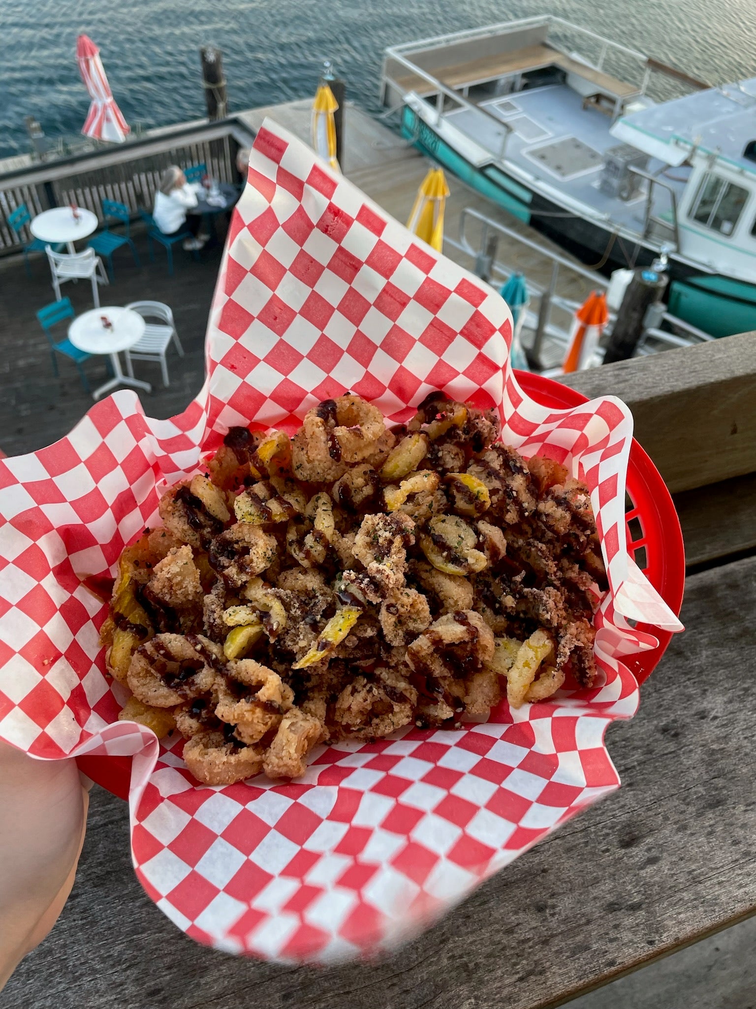 Fried calamari and sides of sauce in a basket lines with red and white wax paper