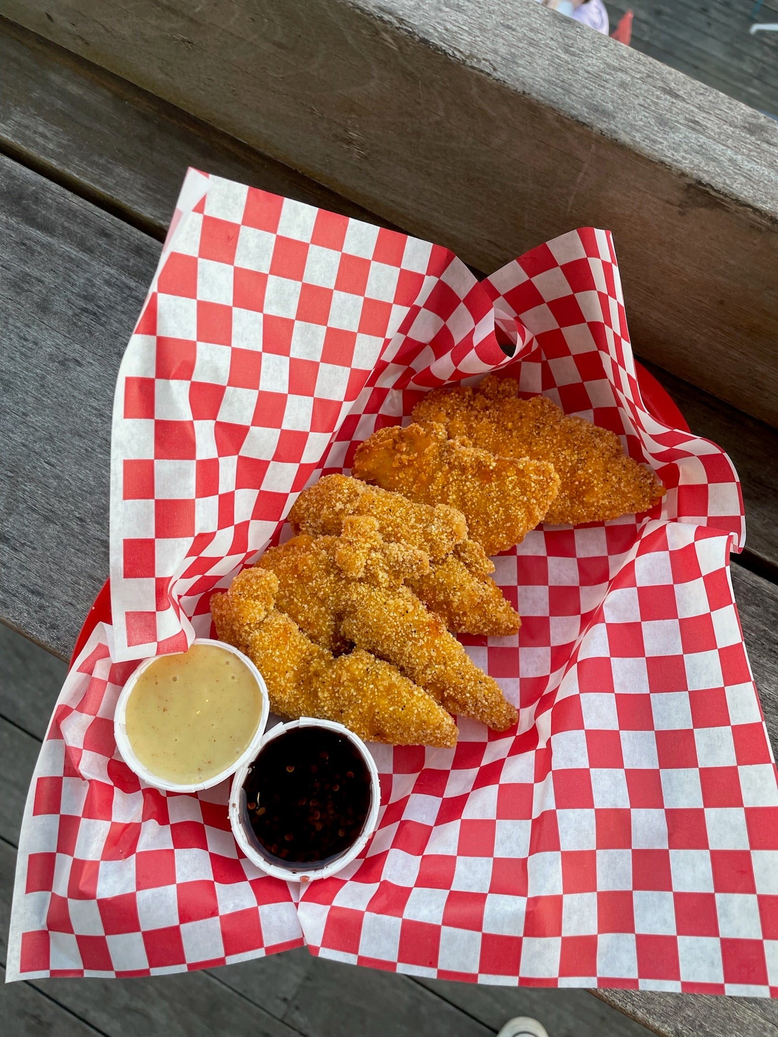 fried chicken tenders in a basket with two sauces