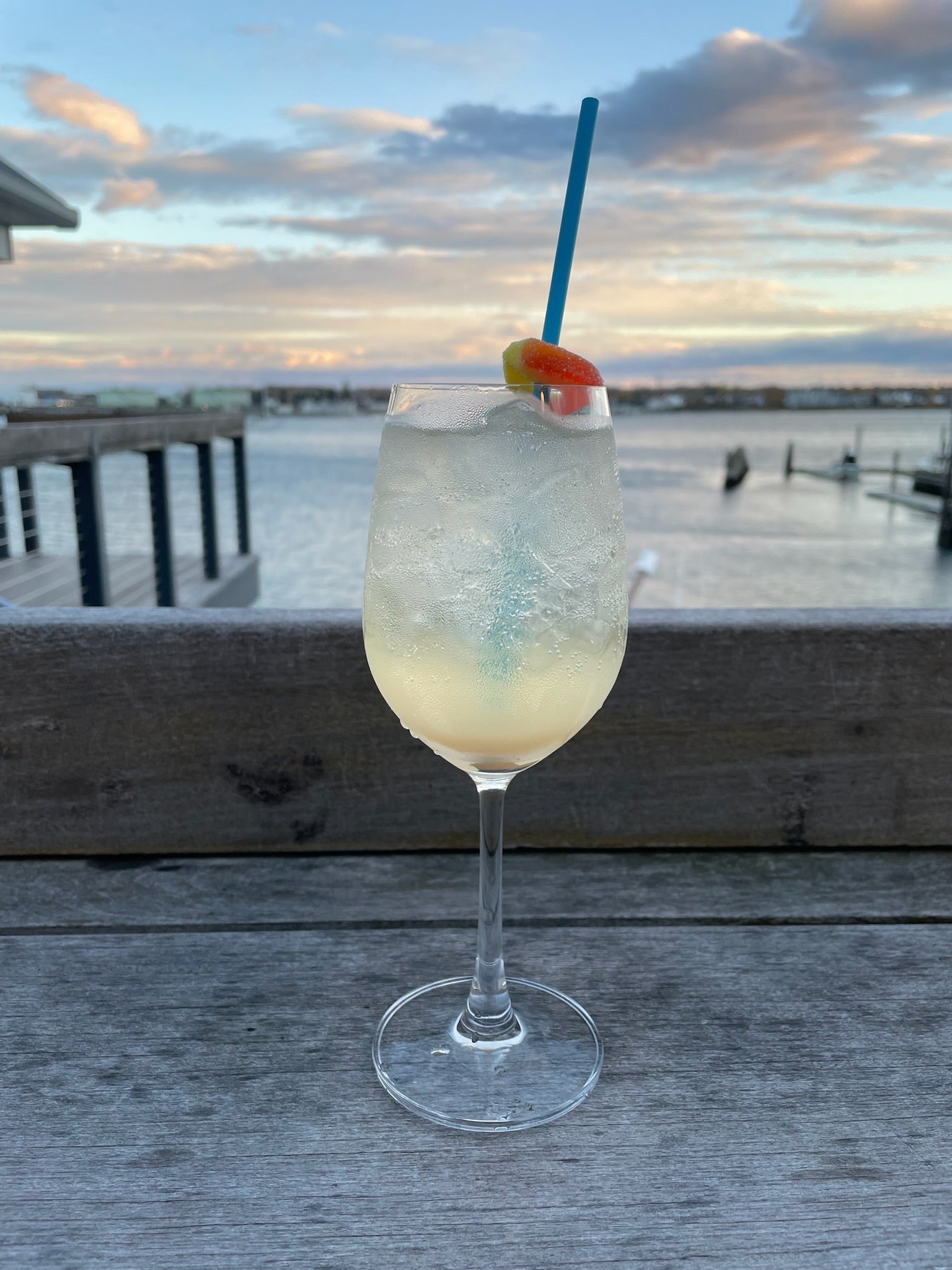 a peach cocktail in a wine glas on the deck overlooking the harbor