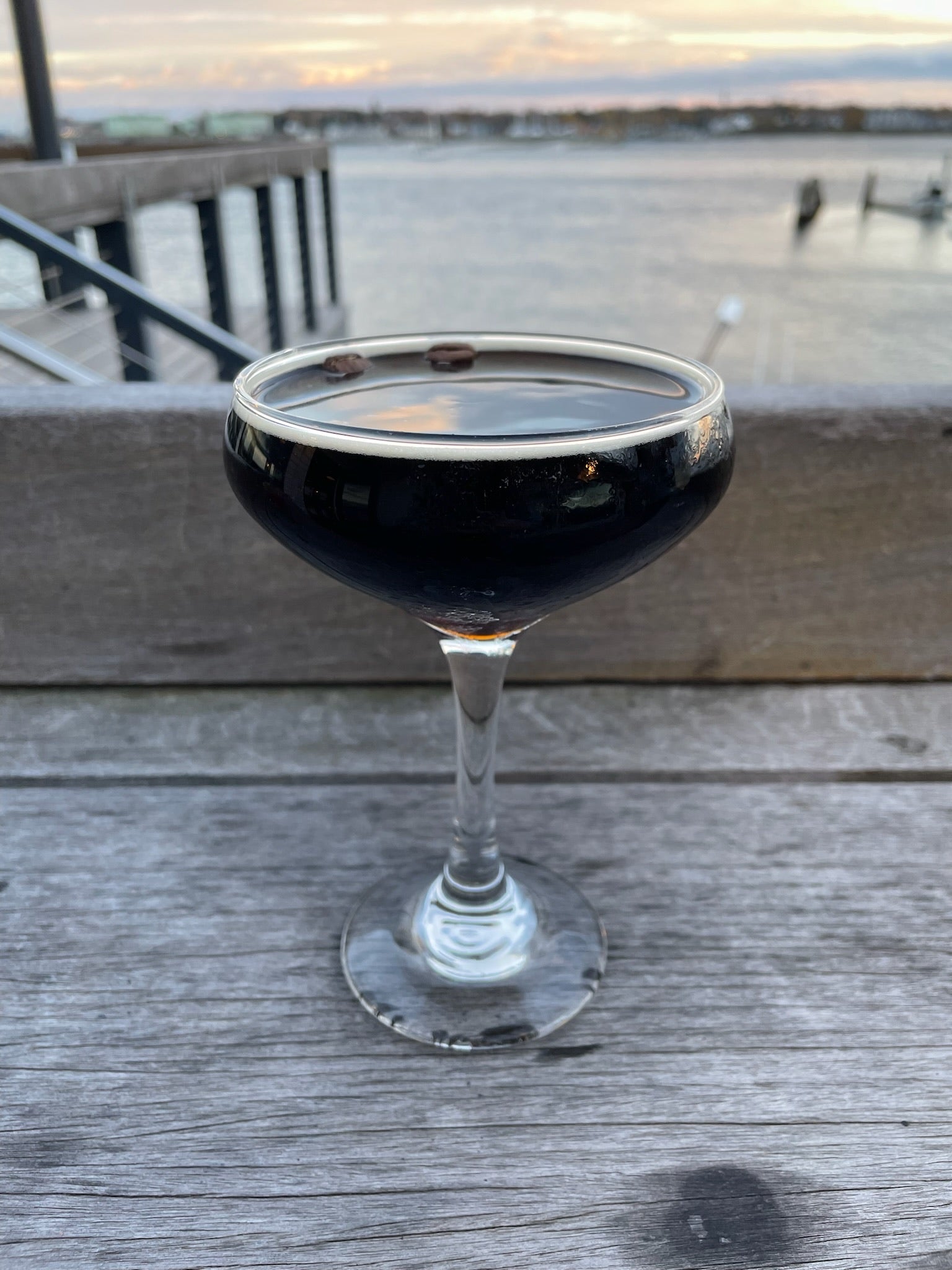 a dark brown cocktail on the deck overlooking the harbor