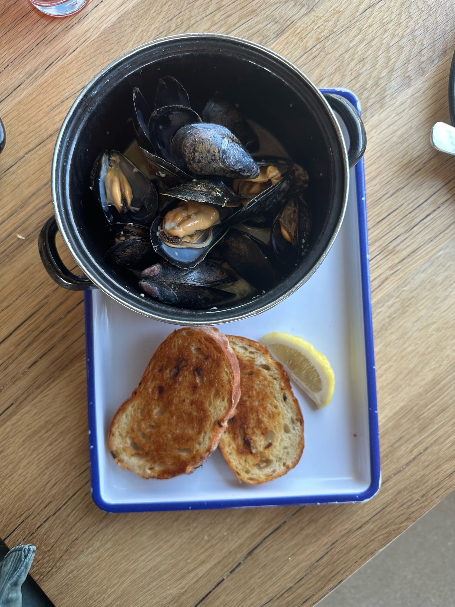 Mussels in a pot with bread on a tray