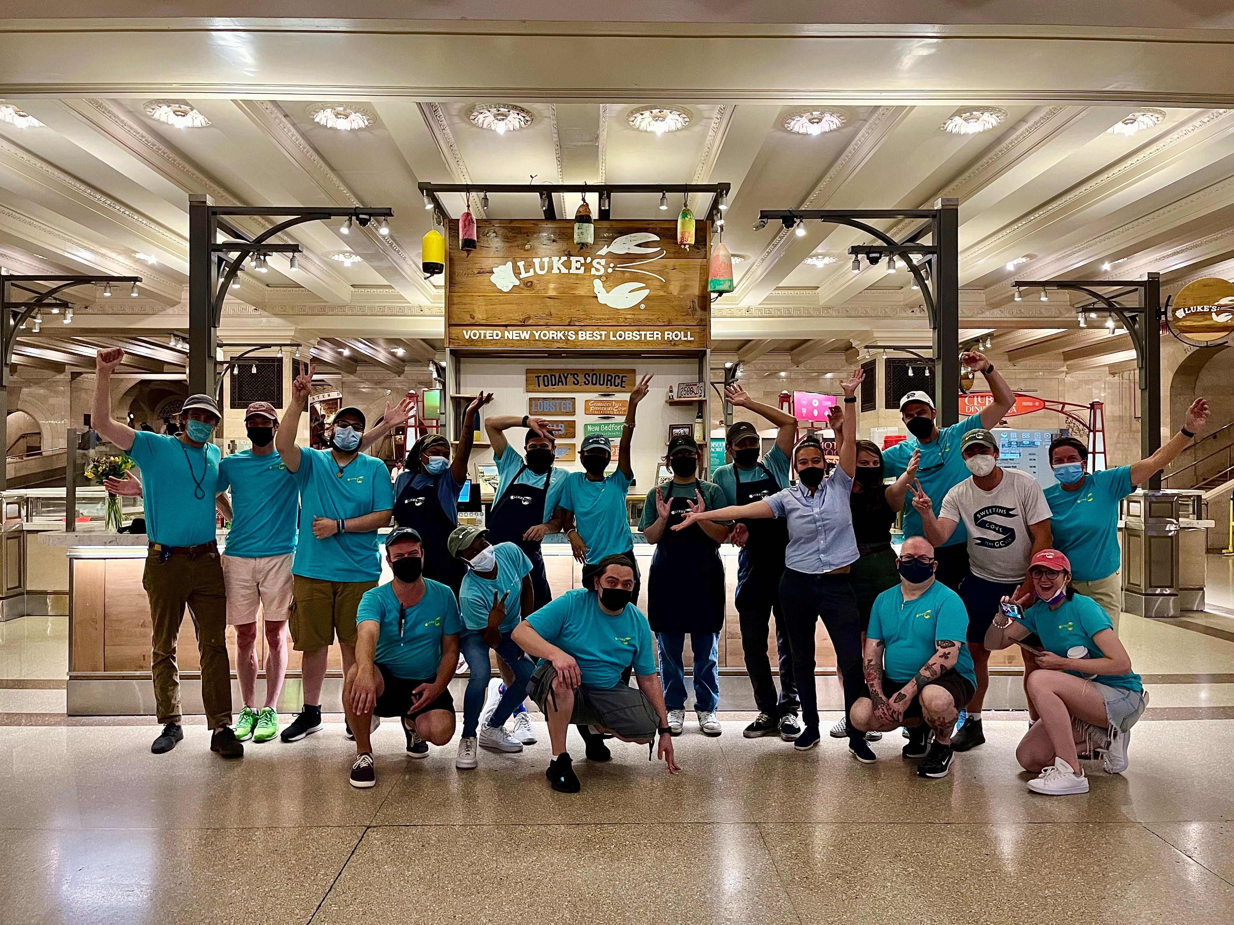 a large group of employees posing in front of luke's lobster Grand Central