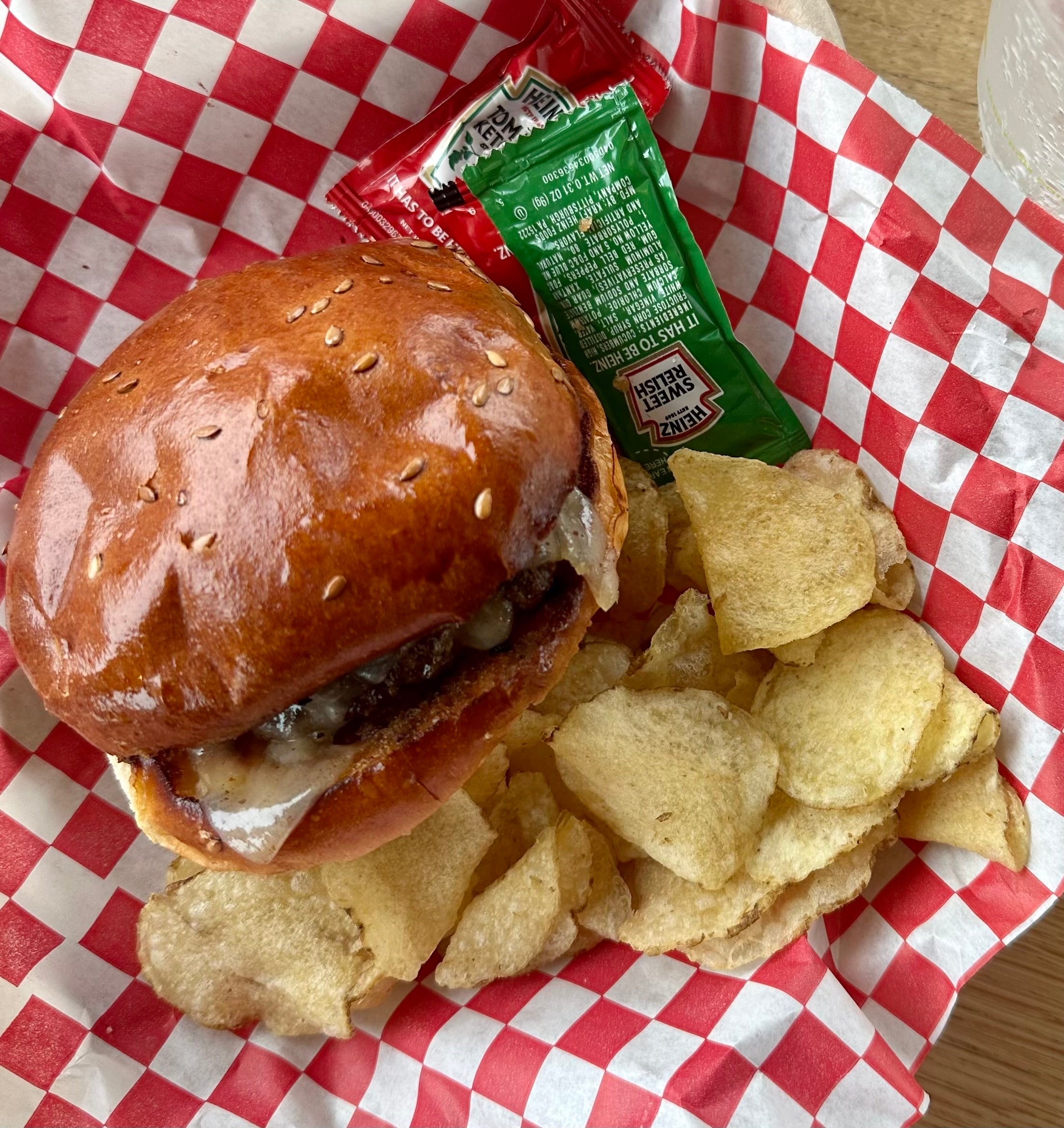 Kids burger with chips and condiment packets in a basket lined with wax paper
