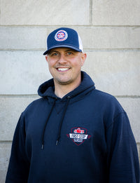 Brett smiling while wearing a navy hat and sweatshirt
