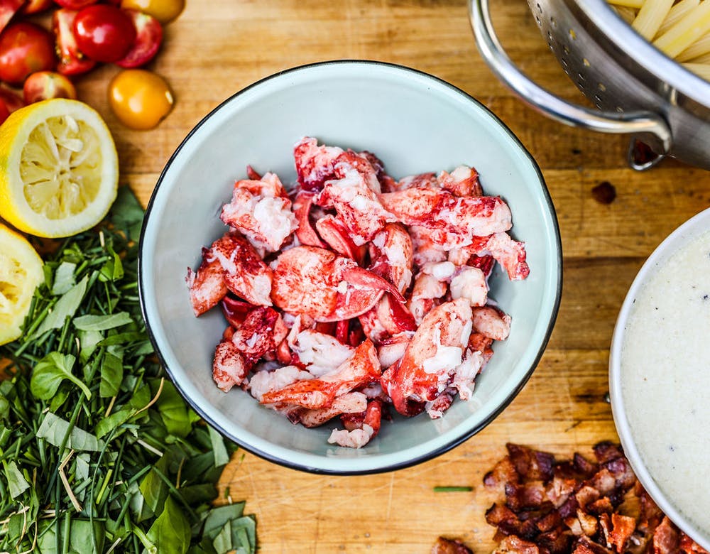 a bowl surrounded by fresh ingredients full of lobster meat 