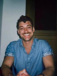 Christian wearing a blue button down shirt smiling for a photo