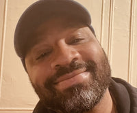 Arturo smiling for a selfie while wearing a baseball hat