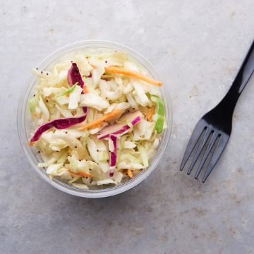 Poppyseed coleslaw in a container on a metal table